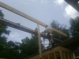 Carpenter setting a ridge beam over a new addition frame — Ice Dam Removal by Roofing Brothers in Kittitas
