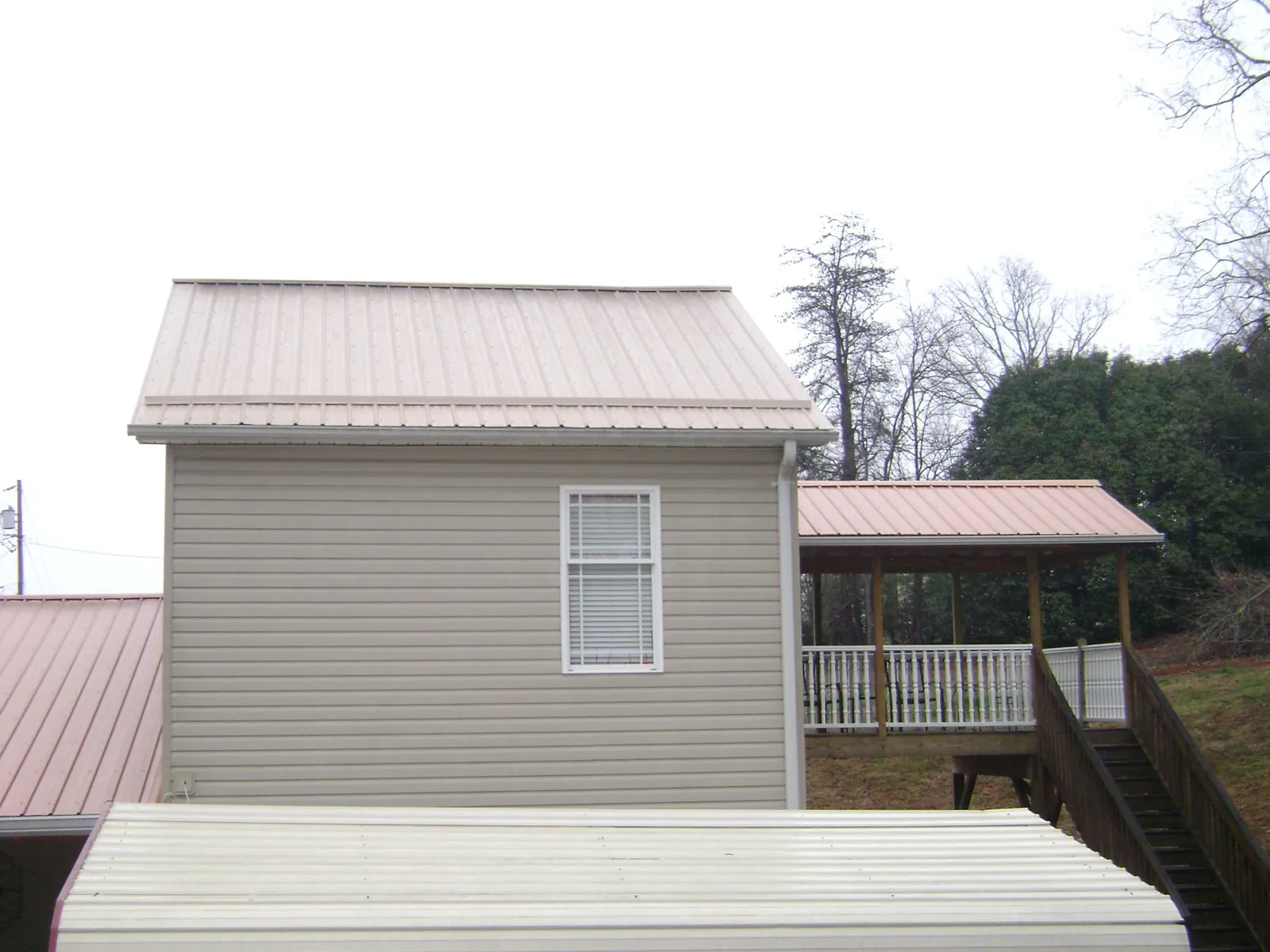 Tan metal roofs on a two story addition and attached porch, from a Roof Replacement job in Kittitas