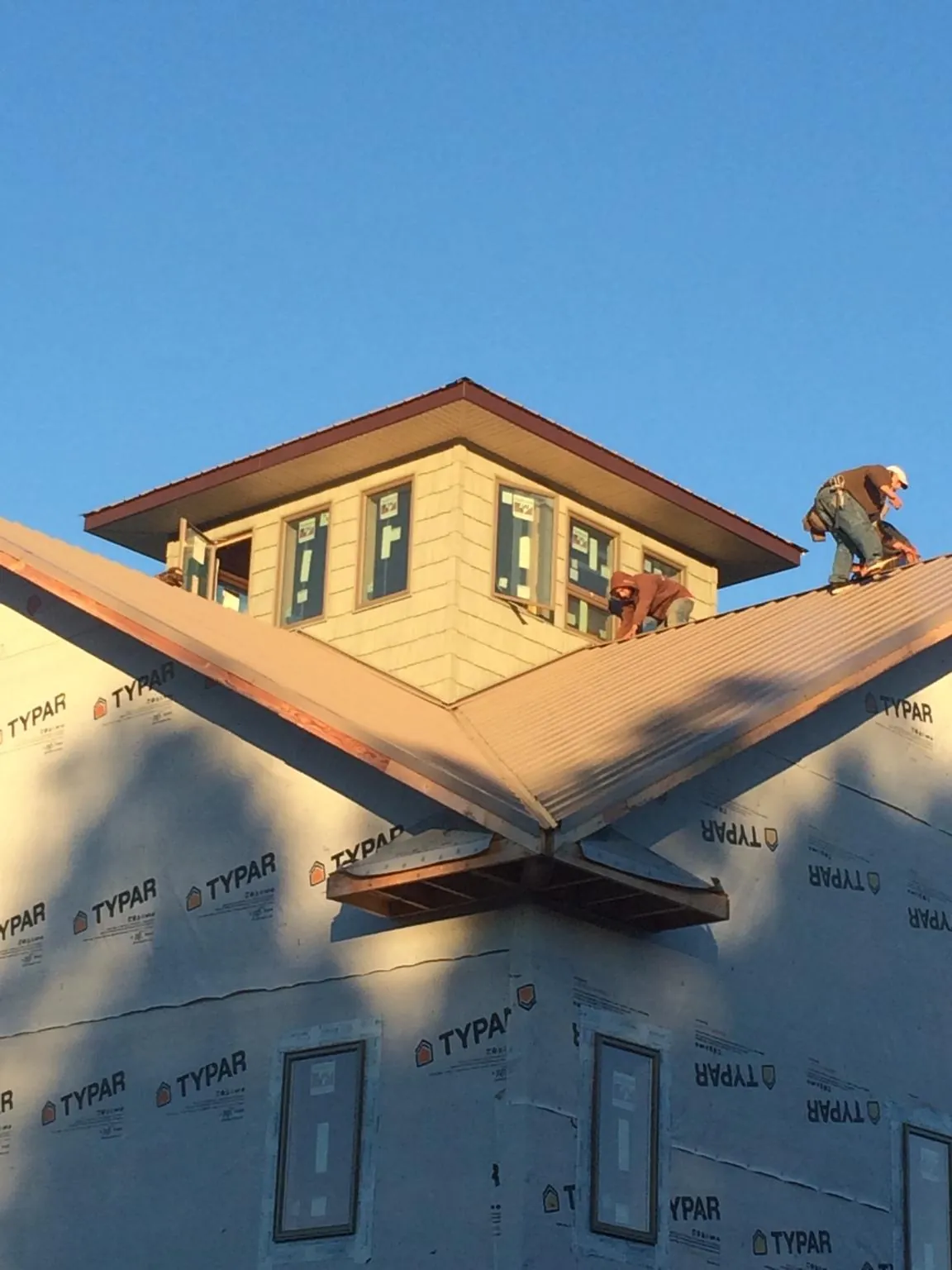 Roofers working around a rooftop cupola on a new metal roof at sunset — Roof Waterproofing in Kittitas by Roofing Brothers